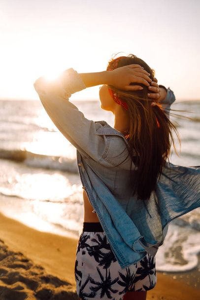 Girl enjoys vacation on the beach at sunset. The concept of relax, travel, freedom and summer vacation. - Foto, Imagen