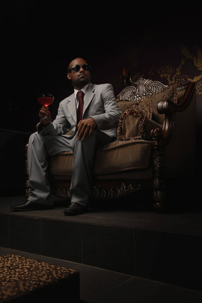 Businessman with sunglasses holding a glass of cocktail - 写真・画像