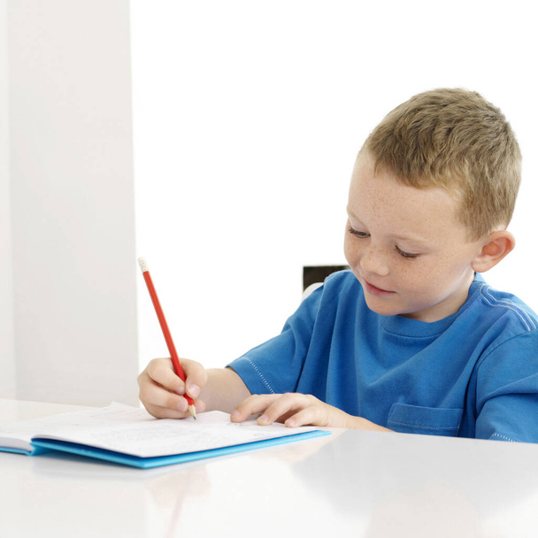 Boy smiling while writing - Zdjęcie, obraz
