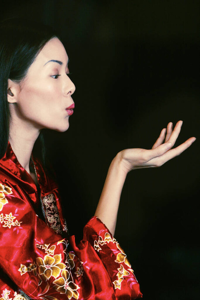 Side shot of a lady in oriental bathrobe blowing a kiss - Fotó, kép