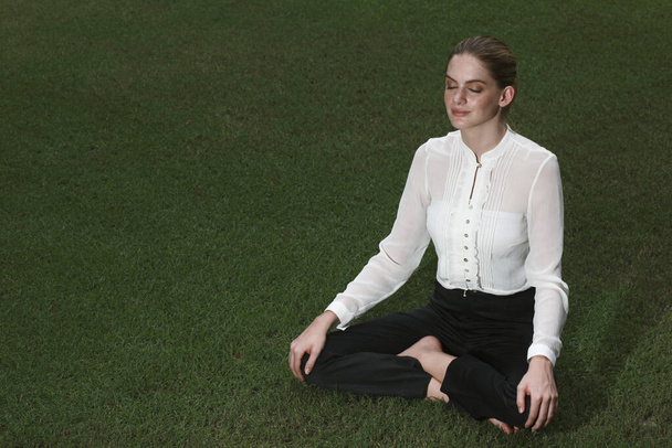 Businesswoman meditating on the field - Foto, Imagen
