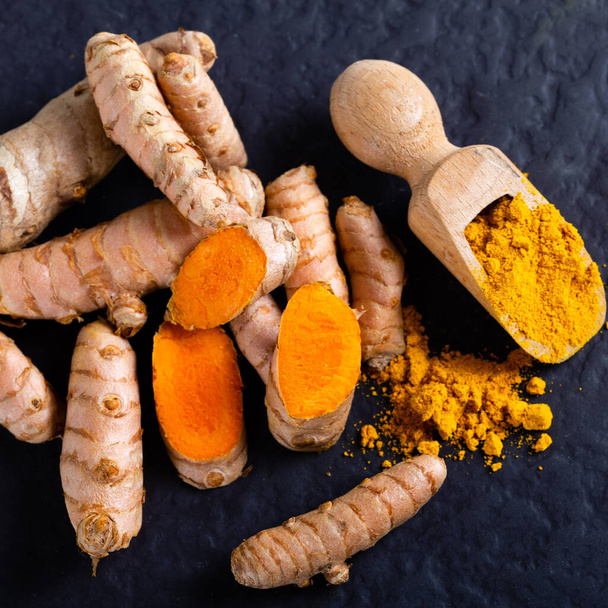 食べ物や飲み物、食事の栄養、健康管理の概念。生の有機オレンジターメリックの根と粉末,すりおろした調理台の上にキューマロンガ.インドのオリエンタル低コレステロールスパイス - 写真・画像