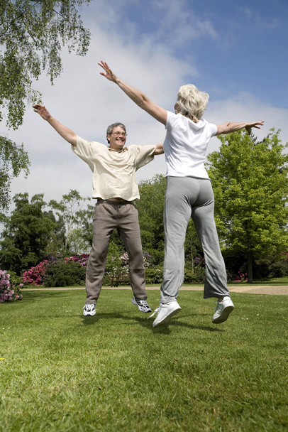 Senior man and woman jumping with their arms outstretched - Foto, immagini
