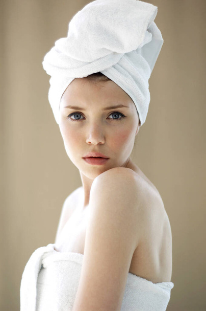 A woman with her hair and body wrapped up in towel looking at the camera - Foto, afbeelding