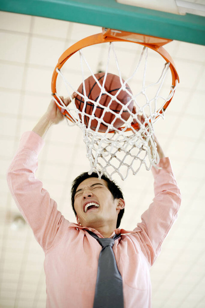 young usinessman dunking basketball - Photo, image