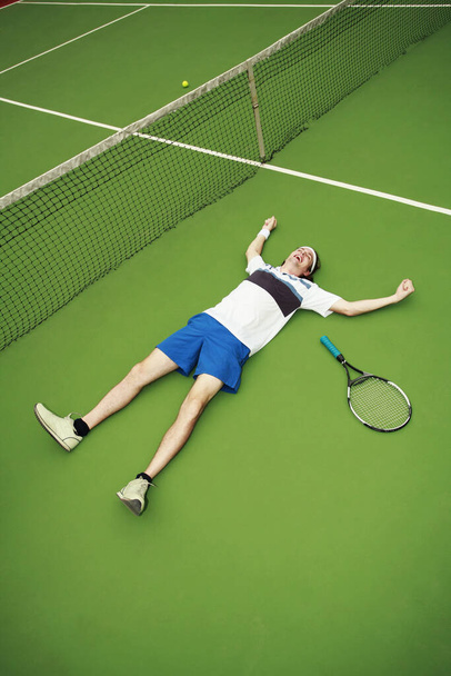 Man lying on the court after winning a match - 写真・画像