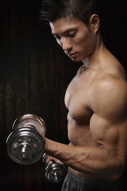Muscular man exercising with dumbbells - Photo, image