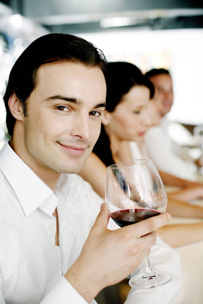 Man holding a glass of red wine while smiling at the camera - Fotoğraf, Görsel