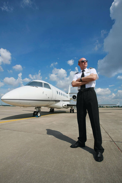 Pilot standing at runway with private jet in the background - Фото, зображення