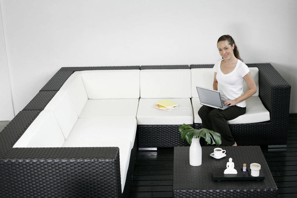 Woman sitting on the couch using laptop - Foto, Bild