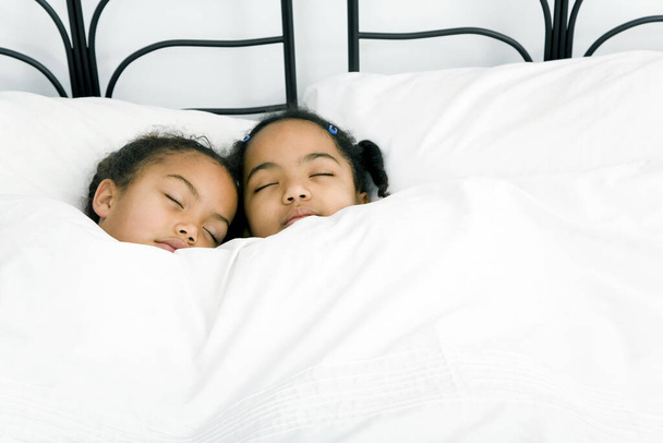 Girls sleeping together on the bed - 写真・画像