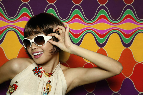 Woman smiling while adjusting her sunglasses - Fotografie, Obrázek