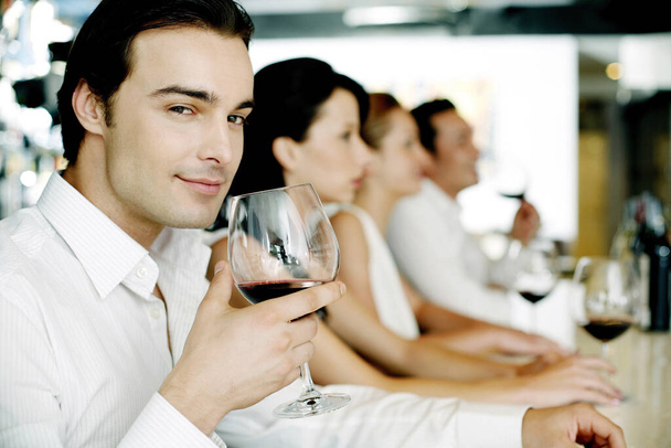 Man holding a glass of red wine while smiling at the camera - Foto, Bild