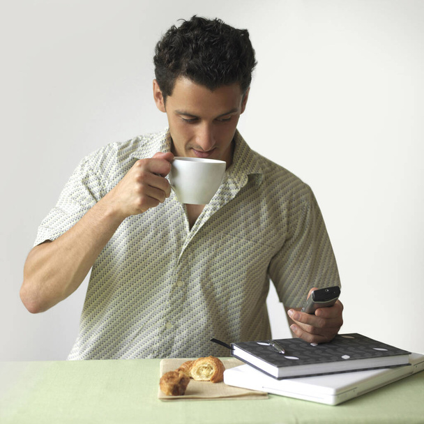Man drinking coffee while text messaging on the mobile phone - Foto, Bild