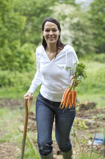 Woman holding carrots and spading fork - Фото, зображення