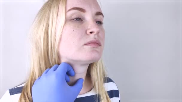 Il medico esamina la ghiandola tiroidea di una ragazza. Le mani nei guanti sentono la sporgenza cartilaginea della laringe. - Filmati, video