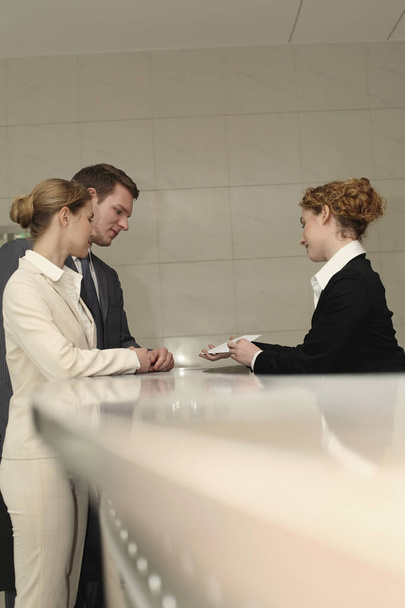 Receptionist passing a letter to businessman and businesswoman - Foto, Imagen