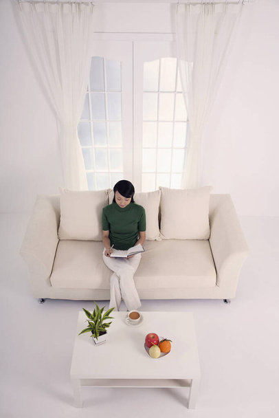 Woman sitting on the couch, writing diary - Фото, зображення