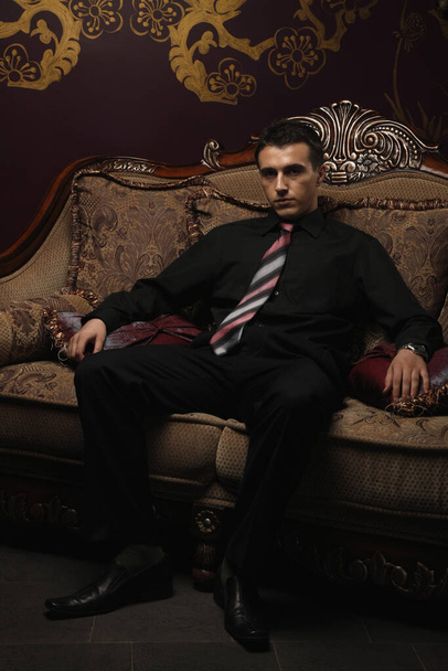 Businessman sitting on antique sofa - Fotoğraf, Görsel