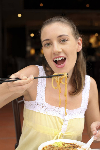 Woman eating noodles with chopsticks - Foto, Imagen