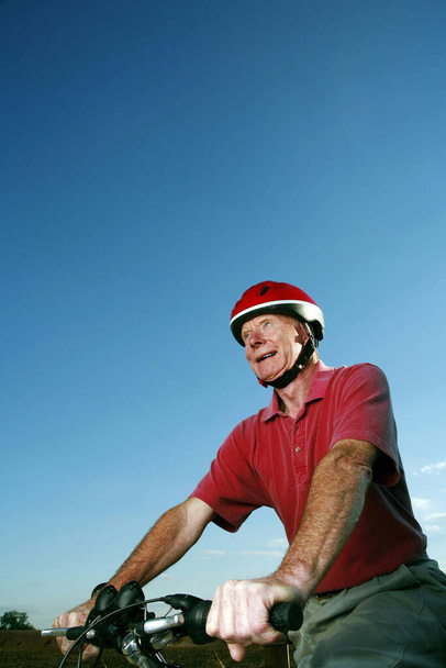 Senior man with helmet riding on bicycle - 写真・画像