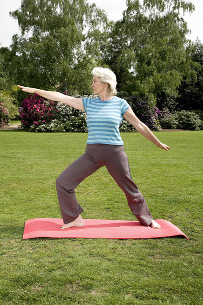 Senior woman practising yoga in the park - Fotoğraf, Görsel