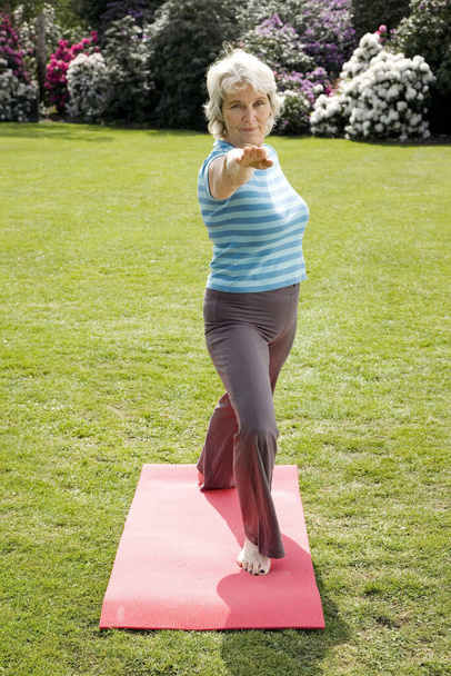 Senior woman practising yoga in the park - 写真・画像