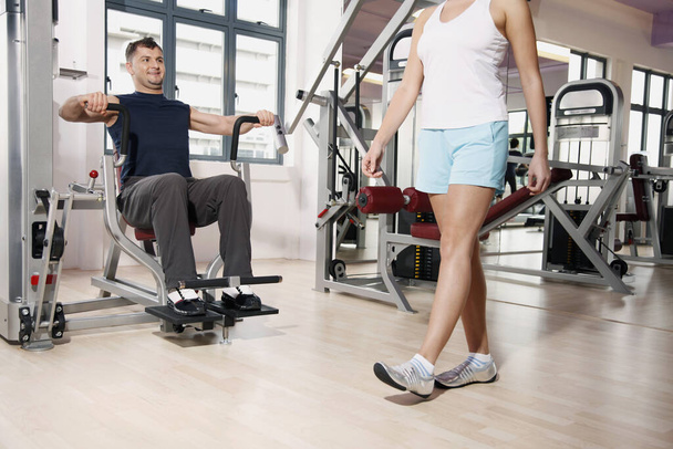 Man checking out woman while exercising in gym - Фото, изображение