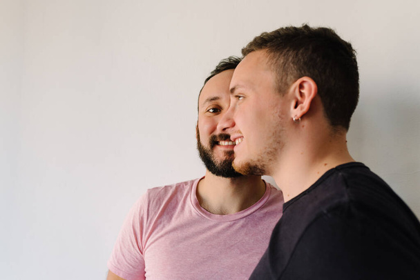 Stock photo of two gay caucasian men standing at home. One of them is facing the camera, the other is facing away. - Photo, Image