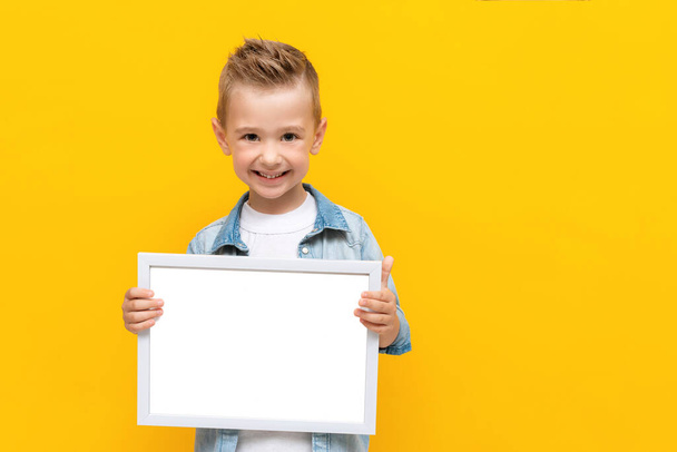 Happy smiling kid holding white frame with copy space for text certificate or diploma - Photo, Image