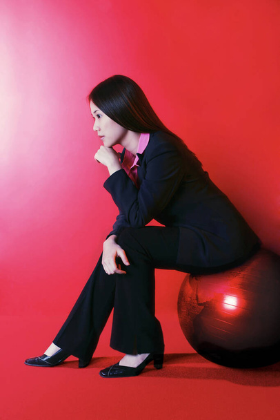 Side shot of a lady sitting on a ball thinking - Фото, изображение