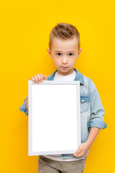 Serious kid holding white frame with copy space for text certificate or diploma - Photo, image