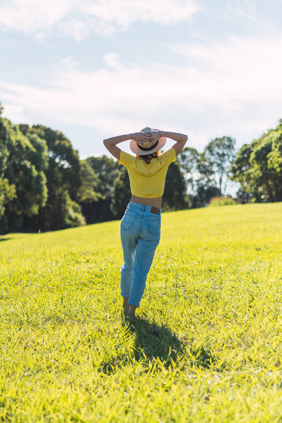 Portrait of a beautiful, cute, sexy girl. Emotion of pleasure, freedom concept, lifestyle. He stands with his back with hat is running on the field. Vertical photo - Photo, Image