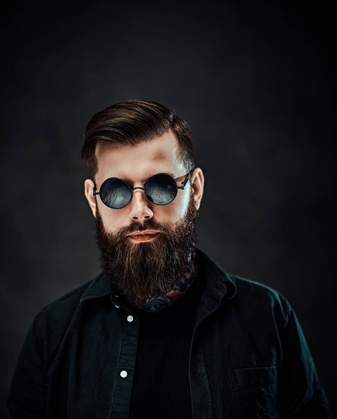 Портрет крутого бородатого мужчины в солнцезащитных очках на темном фоне
 - Фото, изображение