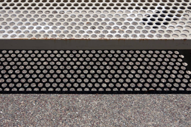 Vue rapprochée en plein cadre d'une section d'un banc de parc jetant son ombre sur le sol en béton caillouteux - Photo, image