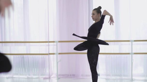 Νεαρή χορεύτρια μπαλέτου χορεύει στο βάθος ενός μεγάλου παραθύρου. - Φωτογραφία, εικόνα
