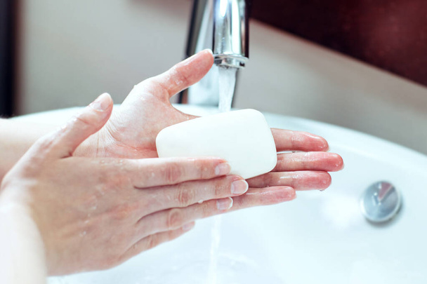 Washing hands. Female hands are being washed with soap in the sink - Фото, зображення