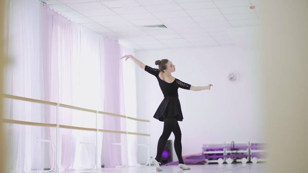 Uma bailarina profissional em um pacote preto dança em um grande salão de treinamento
 - Foto, Imagem