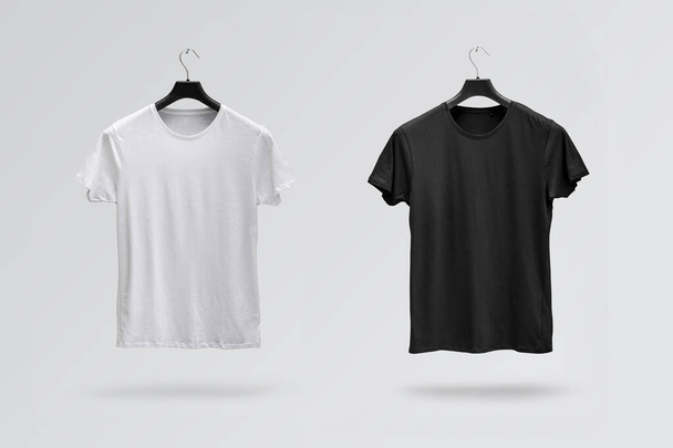 Front sides of male black and white cotton t-shirts on a hanger isolated on white background. T-shirts without print - Valokuva, kuva