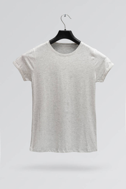 Front side of female grey melange cotton t-shirt on a hanger isolated on a grey background. T-shirt without print. - Fotografie, Obrázek