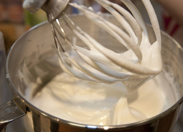 close-up van een chef-kok handen gieten van een suiker mixer - Foto, afbeelding