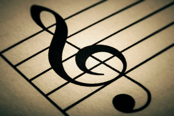 Fekete hármas gomb vagy clef jel makró közelkép nyomtatott egy zenei diagram vagy partíció. Tonozott kép. - Fotó, kép