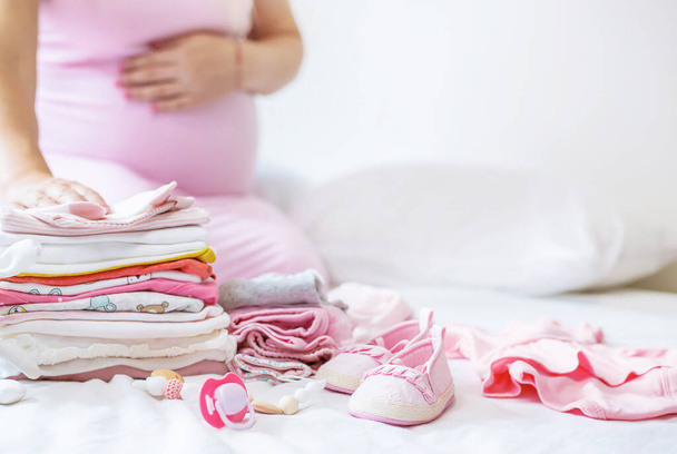 A pregnant woman is folding baby things. Selective focus. people. - Photo, Image
