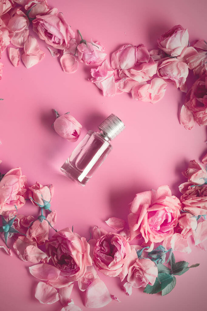  perfume bottle around may roses against pink background - Photo, image