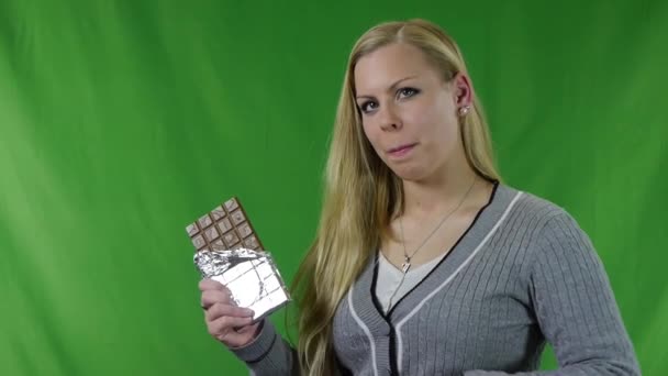 Una mujer joven a la degustación de la barra de chocolate sobre fondo verde
 - Metraje, vídeo