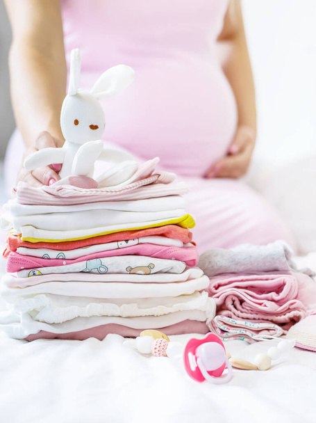 A pregnant woman is folding baby things. Selective focus. people. - Photo, image