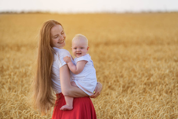 Jovem mãe e criança caminhando no campo e divertido sorriso. Mãe segurando pequena filha ao ar livre
. - Foto, Imagem
