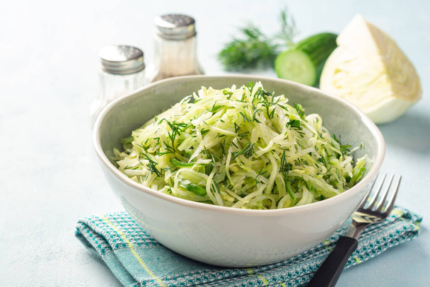 Fresh cabbage and cucumber salad with dill in bowl on concrete background. Coleslaw. Selective focus. - Photo, Image