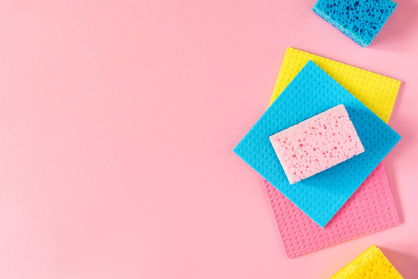 Paños multicolores y esponjas de limpieza sobre fondo rosa
 - Foto, imagen