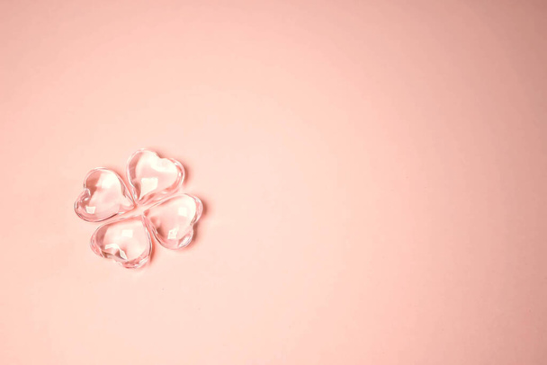 Imitação de um trevo de quatro folhas afortunado com quatro corações de vidro em um fundo rosa para o Dia de St. Patricks. Espaço para texto, conceito de design de textura digital
 - Foto, Imagem